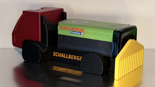 Seitliche Ansicht des AEBI Transporters mit Schallberger Pumpfass und gelbem Anbauteil