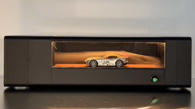 Schwarzes 3D-gedrucktes Windkanal-Display mit Modellauto, warmem Licht und sichtbarer Luftströmung
